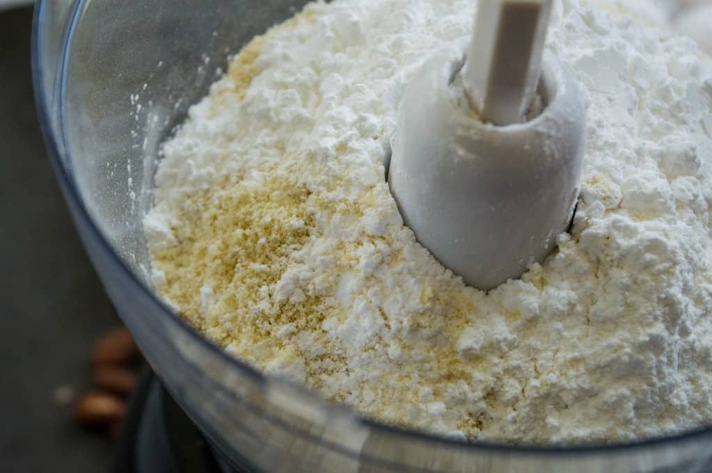 almond flour and powdered sugar in food processor bowl ready to pulse. 