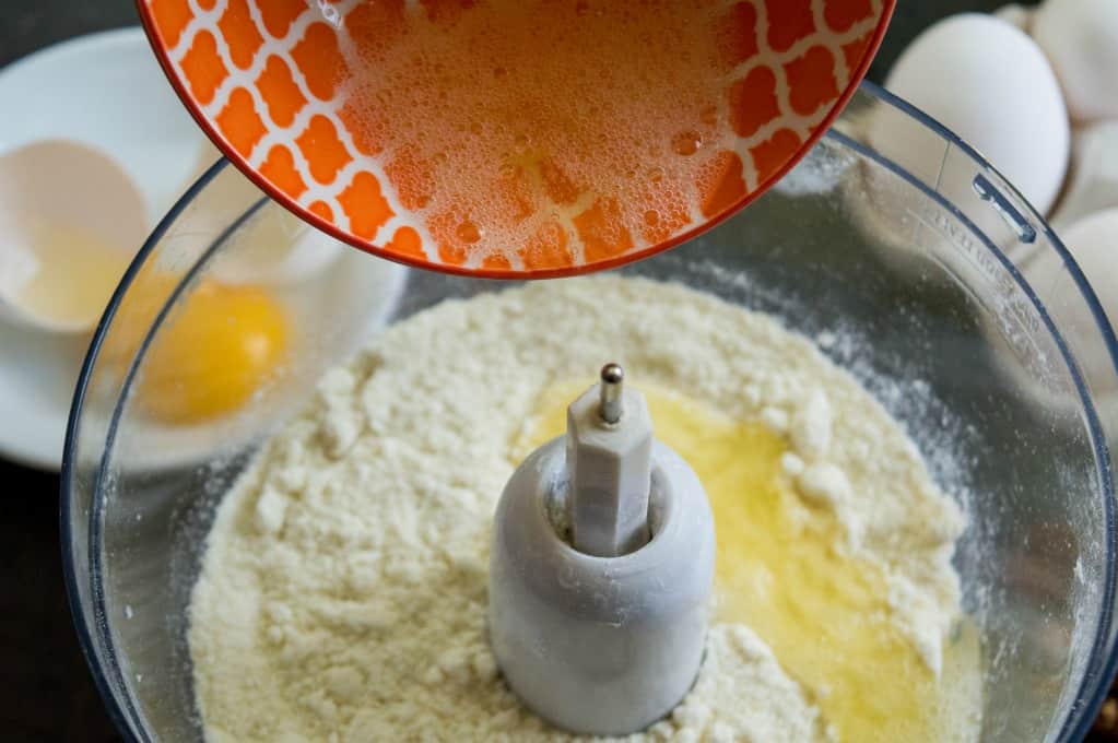 adding the egg whites to the food processor bowl with the other almond paste ingredients