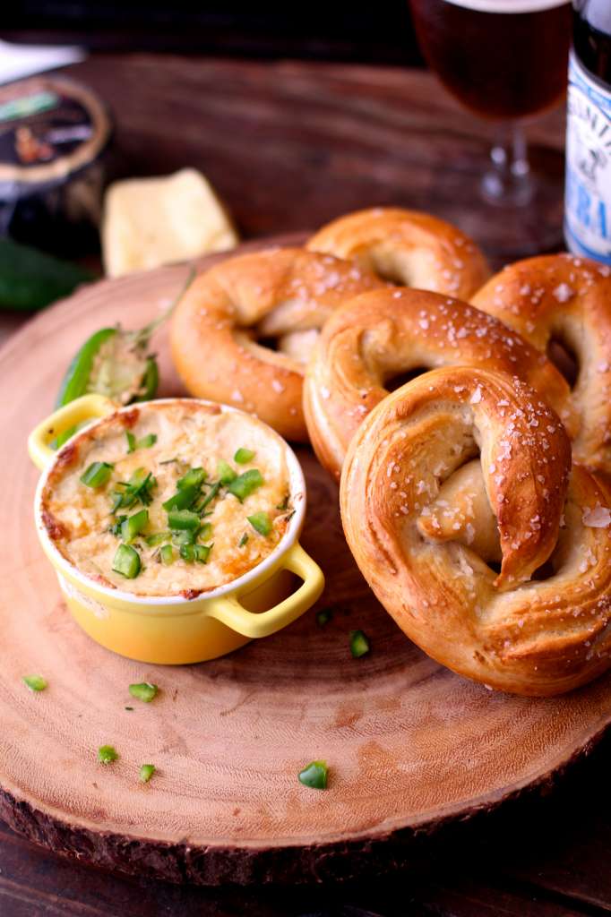 pretzels and beer cheese on round wood cutting board. 