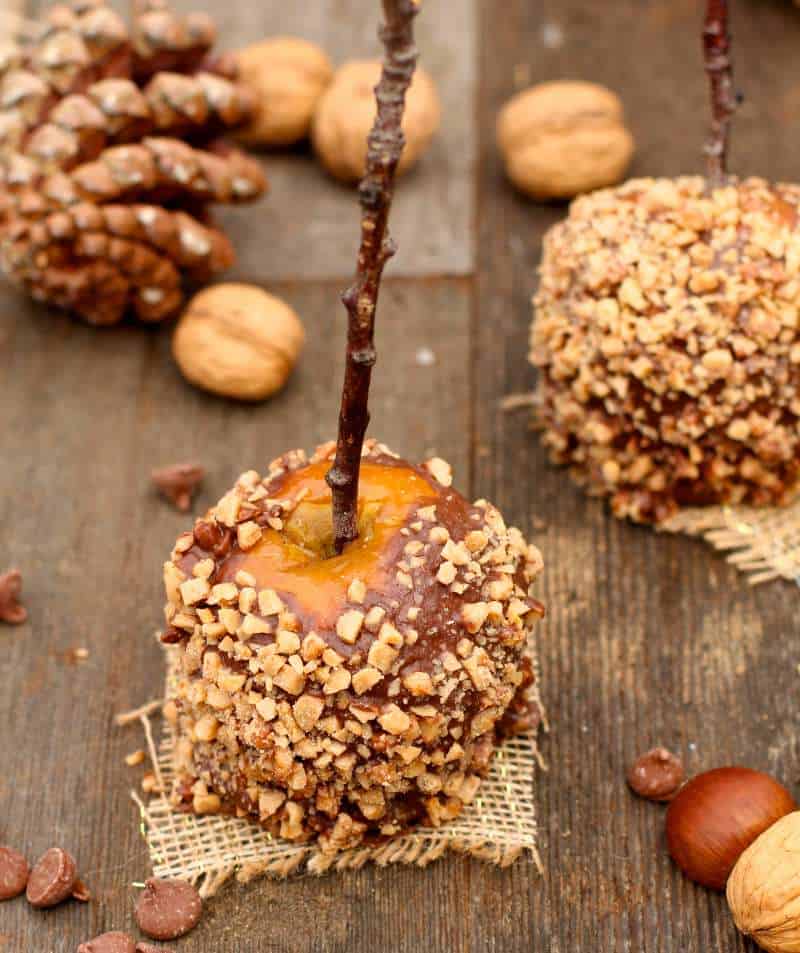 Caramel Apples on wood background with fresh walnuts around. 