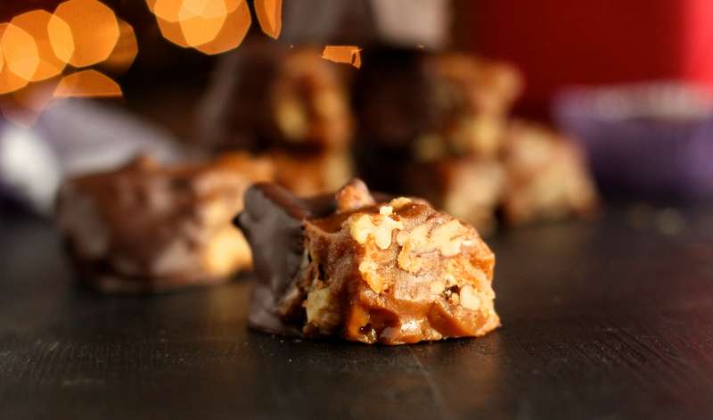 Close up shot of a piece of California brittle where you can see the layers of candy and nuts. 