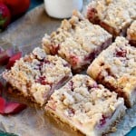 strawberry rhubarb sugar cookie bars cut into six pieces next to a glass of milk