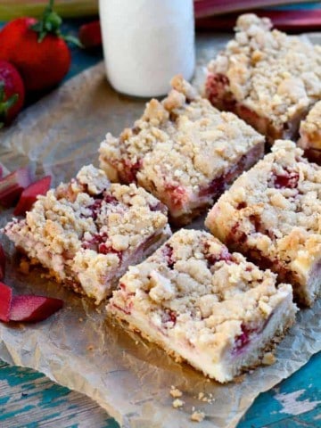 strawberry rhubarb sugar cookie bars cut into six pieces next to a glass of milk