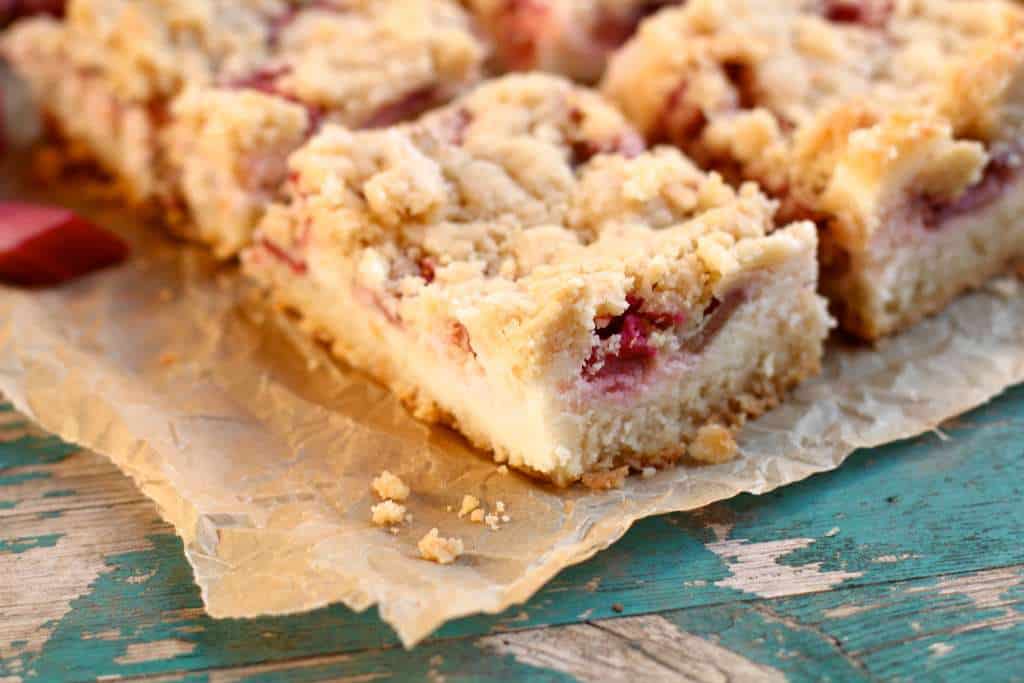 closeup of piece of strawberry rhubarb sugar cookie bars on parchment paper