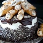 Layered cake with rich ricotta cannoli filling topped with an italian buttercream and homemade mini cannolis