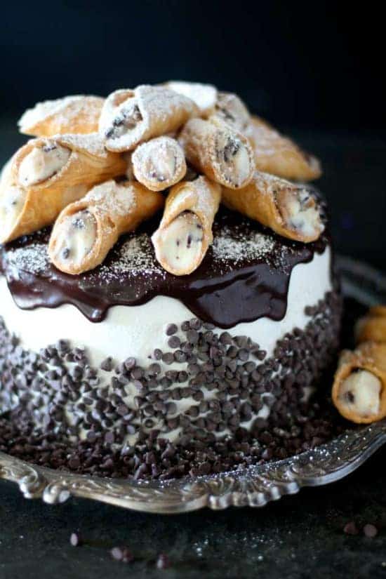Layered cake with rich ricotta cannoli filling topped with an italian buttercream and homemade mini cannolis