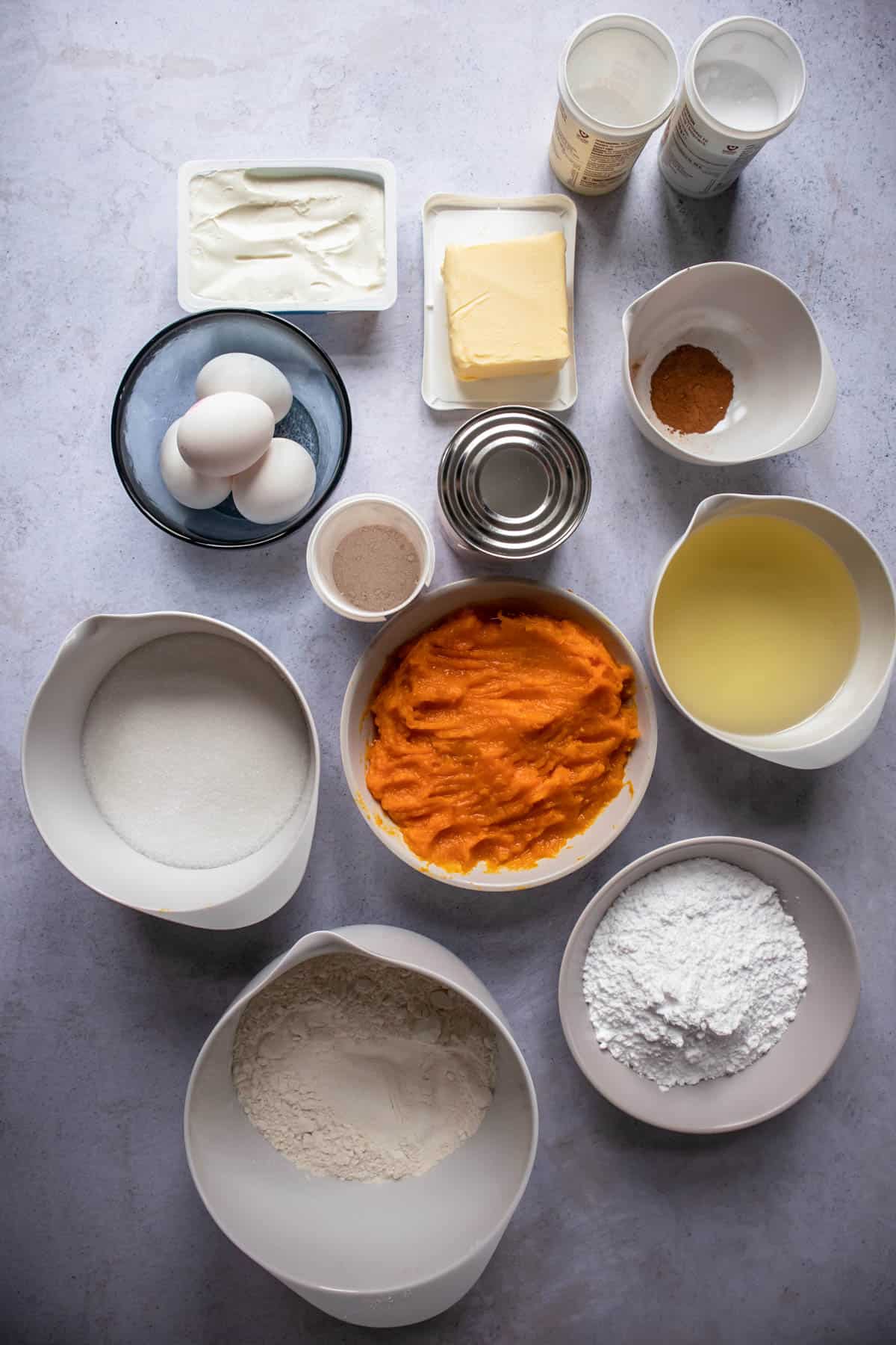 All the ingredients to make the pumpkin dulce de leche cake in small white bowls. 