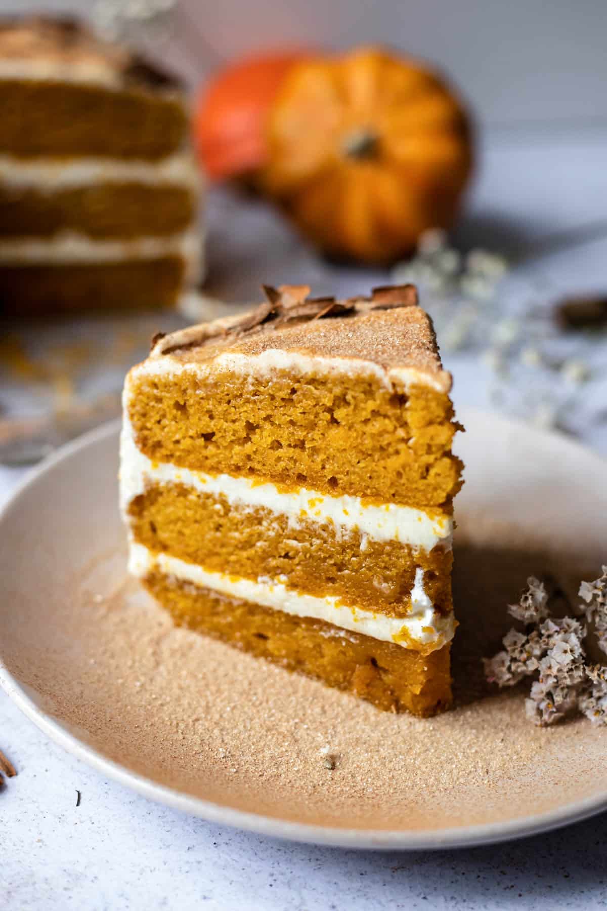Slice of pumpkin cake on. small white dish with whole cake in background. 