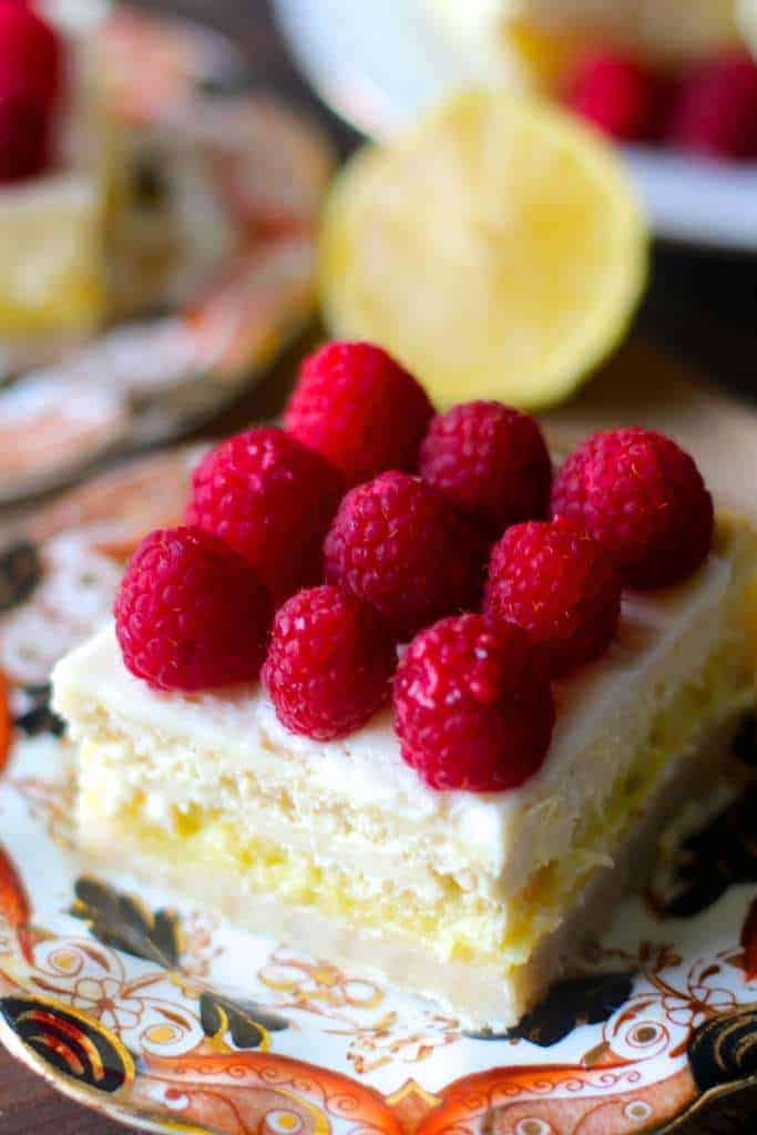 focus shot of lemon cheesecake bars square with nine fresh raspberries on top