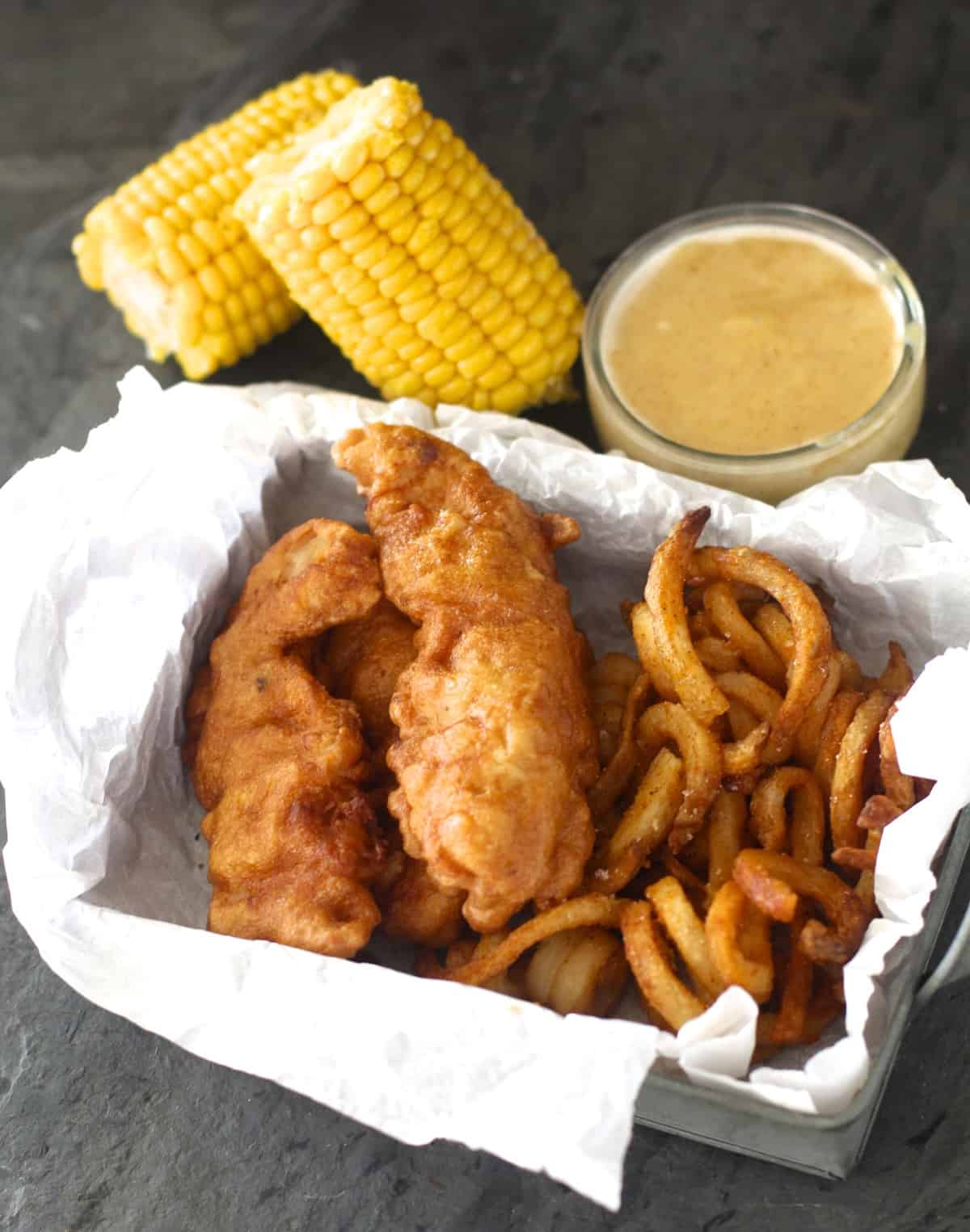 chili's chicken crispers served in a basket next to curly fries and corn on the cob