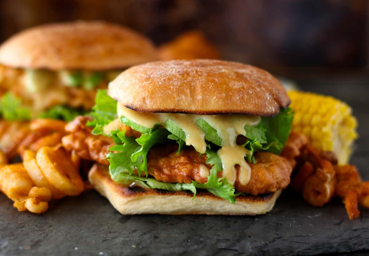 copycat Cchili's chicken crispers in sandwich form with honey mustard dressing and lettuce next to curly fries