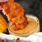 Hand dipping the chicken finger into the honey mustard dressing.