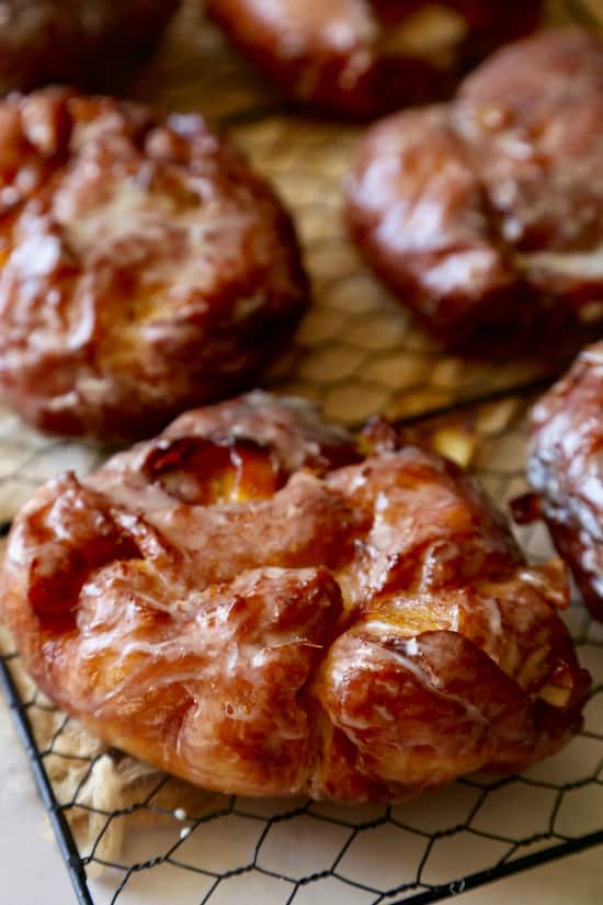 Crisp Donut Shop Apple Fritter donuts on a cooling rack after being glazed.