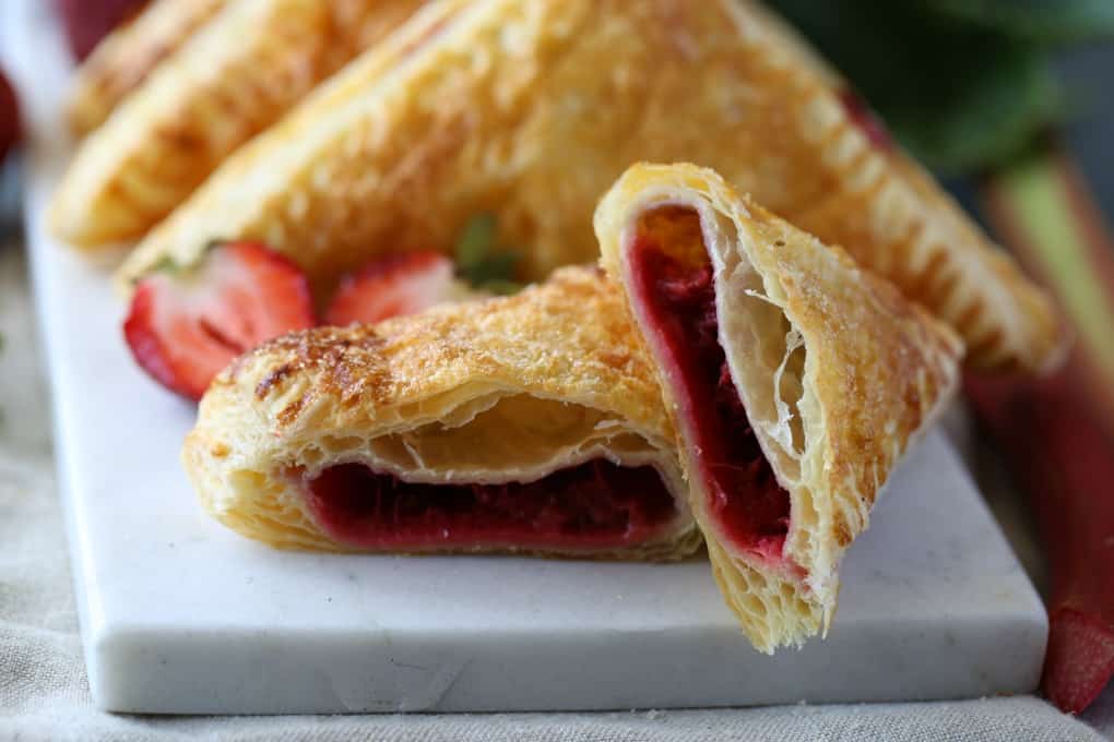 Turnover cut in half showing the strawberry rhubarb cooked fruit center.