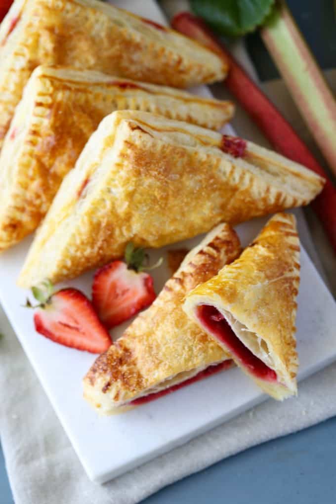 Turnovers on white plate with one cut in half showing the center and fresh berries. 