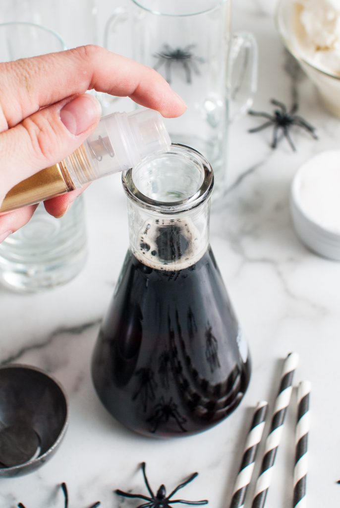 Adding the gold luster dust to the beaker of black root beer. 