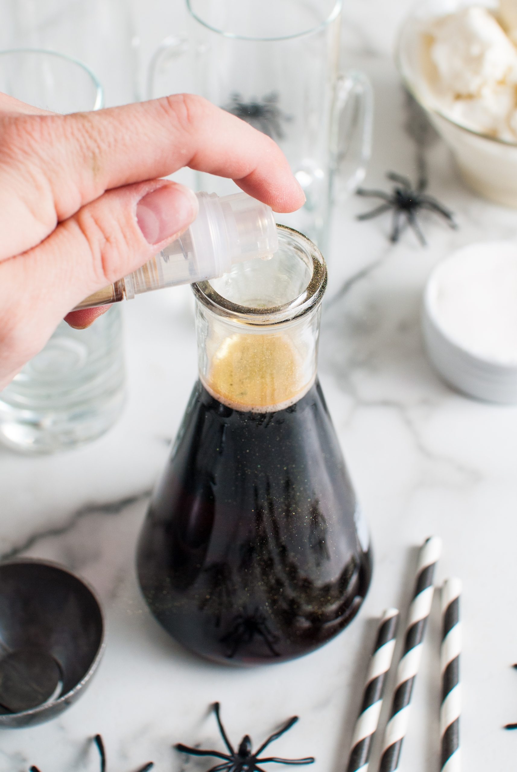 Gold luster dust into a beaker of black root beer. 