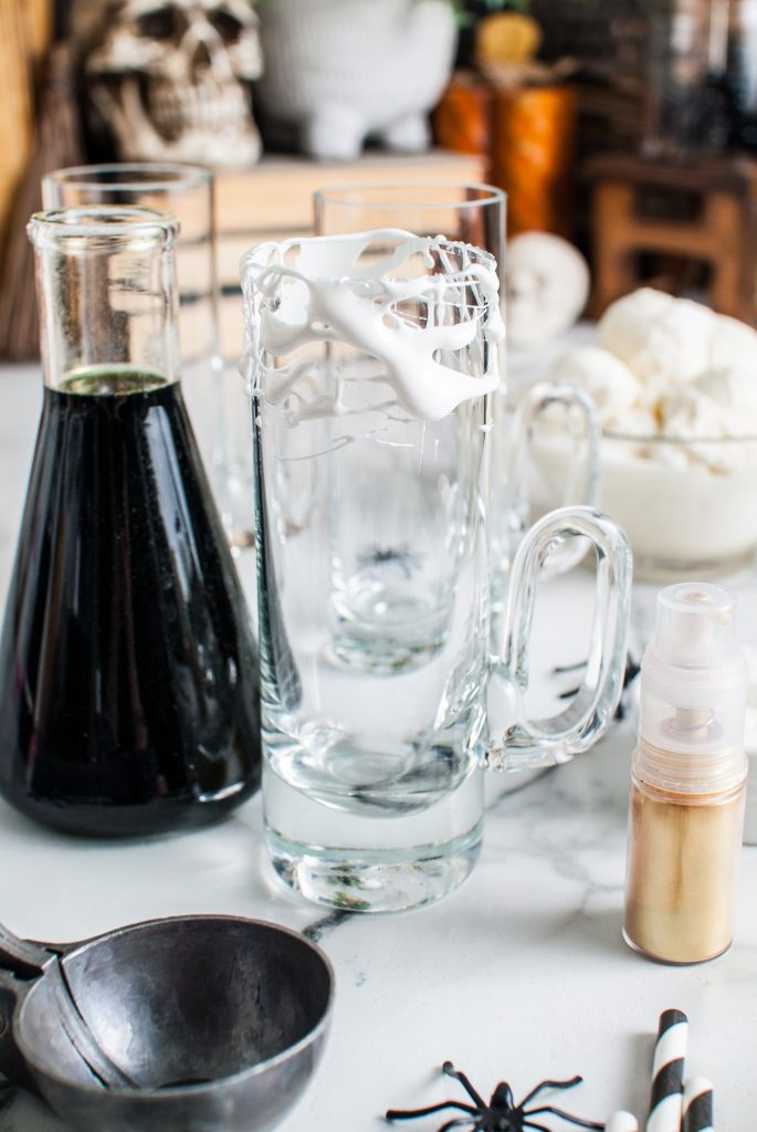 Photo of the marshmallow rimmed glass and beaker of black root beer. 