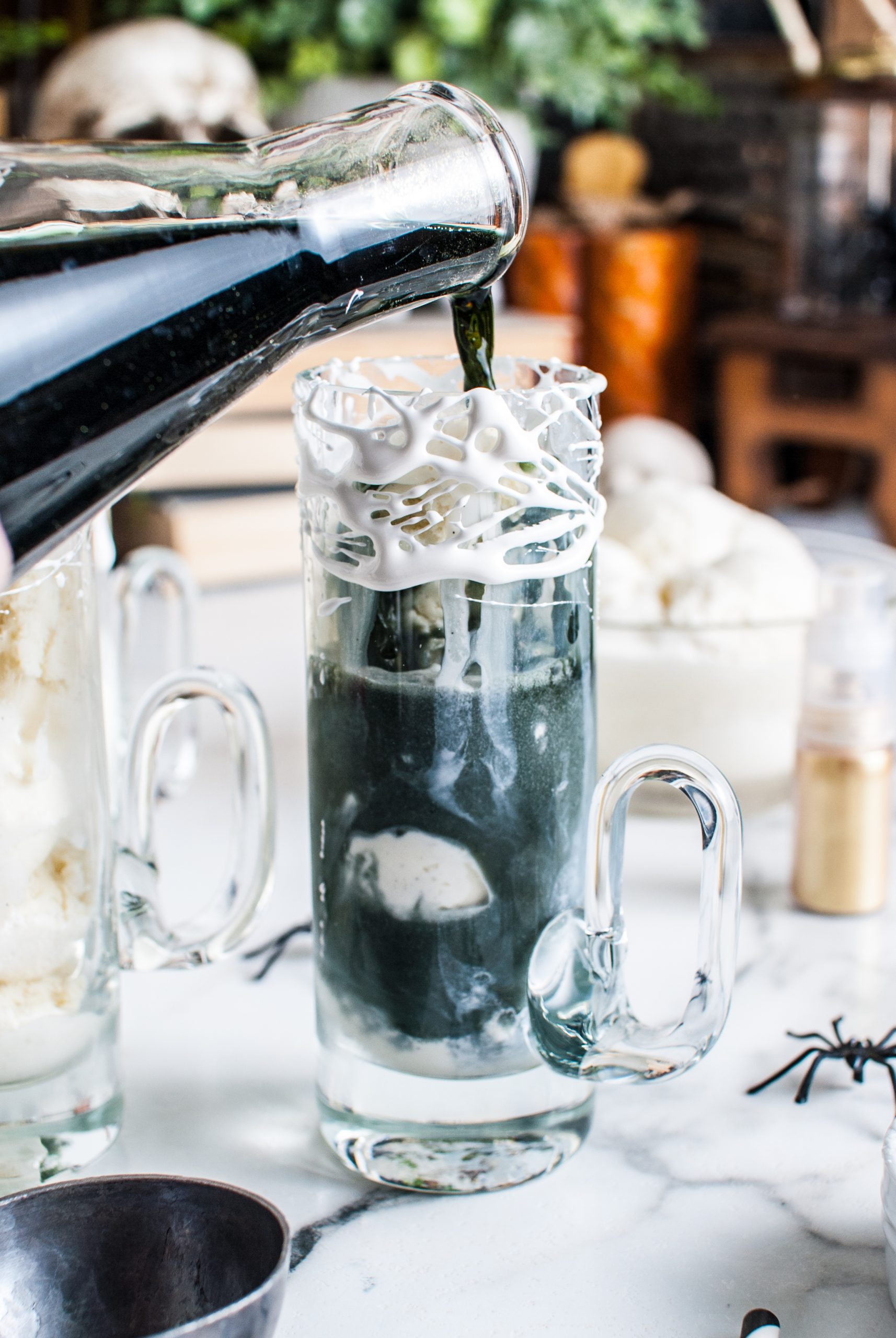 Pouring the black root beer into the glass with scoops of ice cream. 