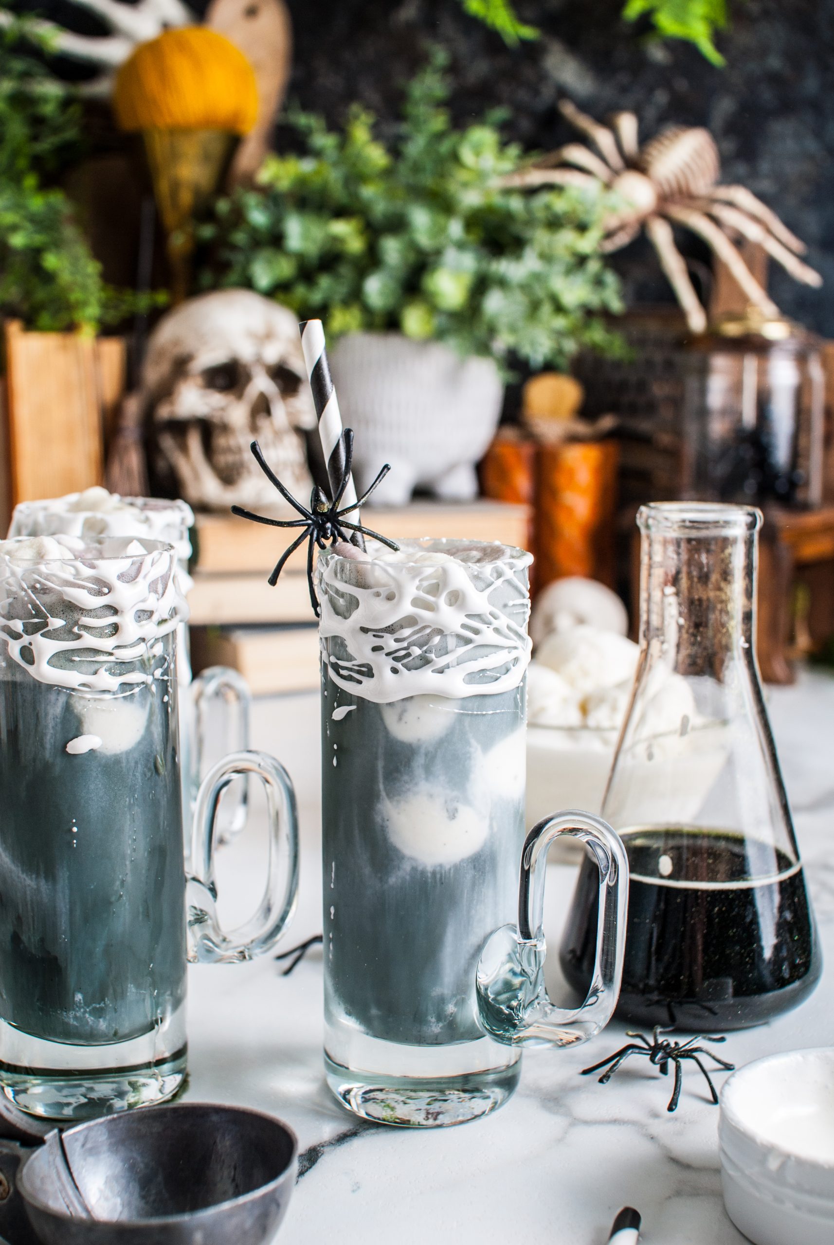 Glasses with black root beer floats and a beaker with black liquid next to it. 