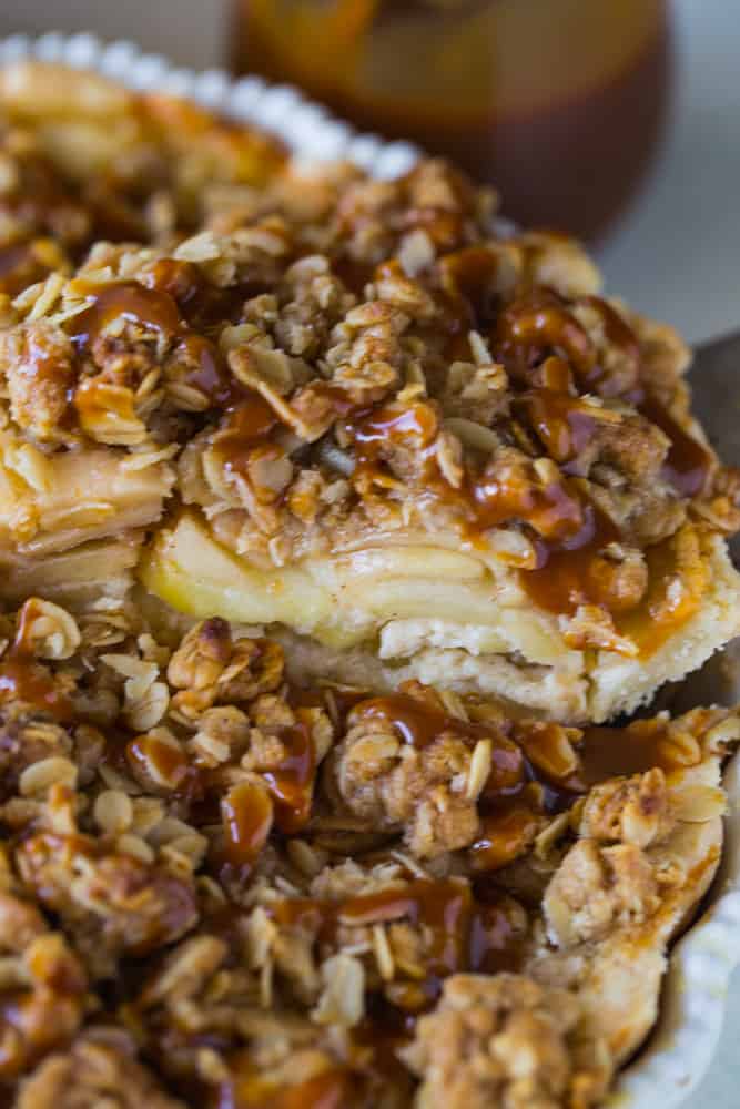 Taking a slice of pie from the pan and showing the layers of streusel and apples. 