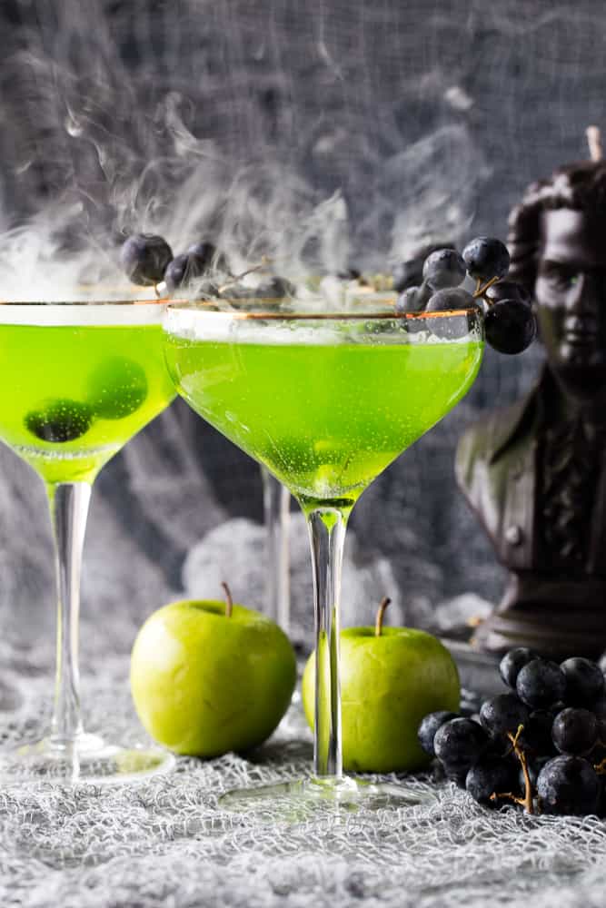 Poison Apple Cocktails that have a green tint and dry ice adding a smoke effect. 