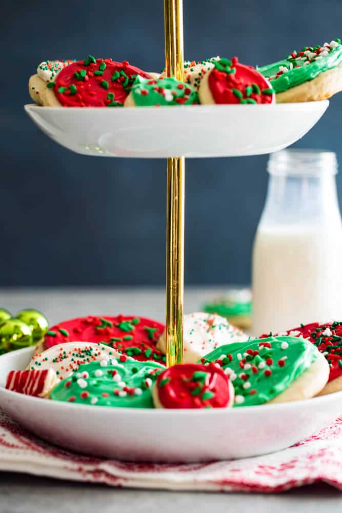 Cookies arranged on a white and gold 2 tier cookie platter with a blue background. 