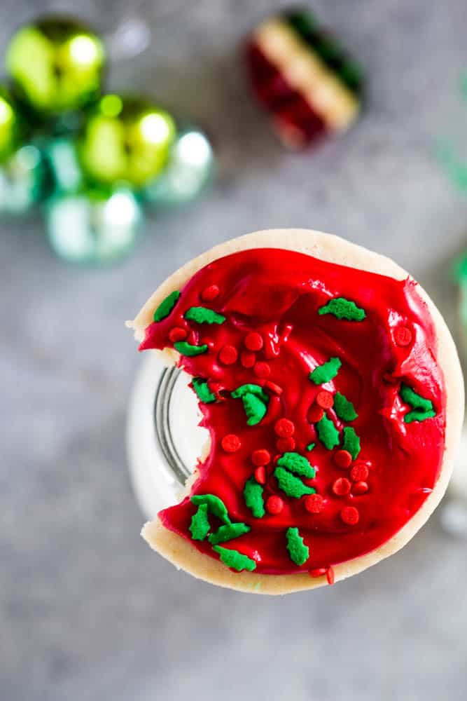 Overhead shot of the cookie with red frosting with a bite taken out of it on a jar of milk. 