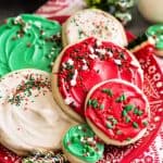 Christmas decorated round sugar cookies on a red and white plate.