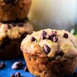 Square image of the chocolate chip zucchini muffins with milk in background.