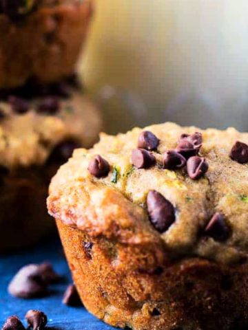 Square image of the chocolate chip zucchini muffins with milk in background.