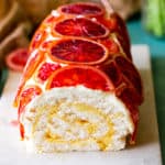 Blood Orange Roulade on white marble cutting board with tan dish towel in background.