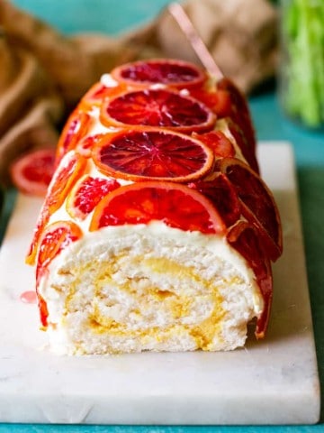 Blood Orange Roulade on white marble cutting board with tan dish towel in background.