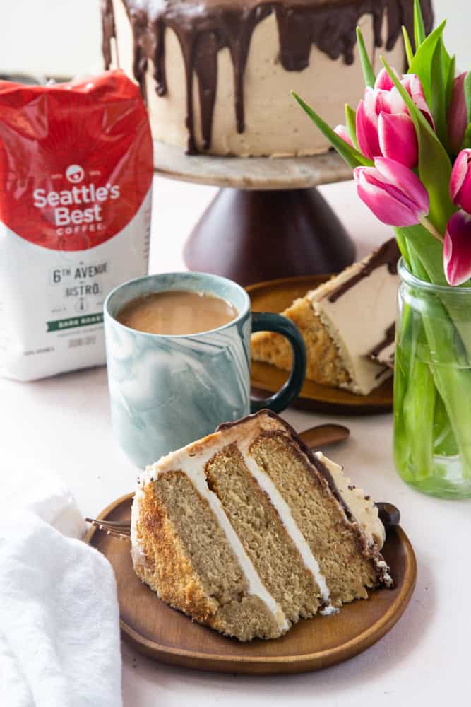 Cake slices on wooden cake plates with a green marble coffee cup and fresh tulips in background. 