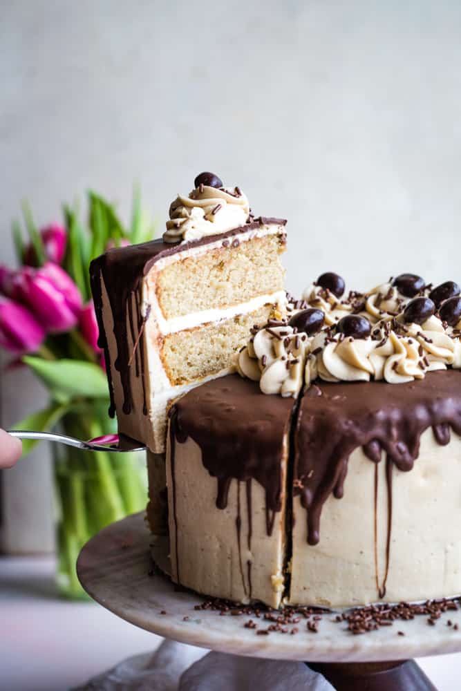 Up close photo of a hand using a cake slicer to remove a slice out of the cake.