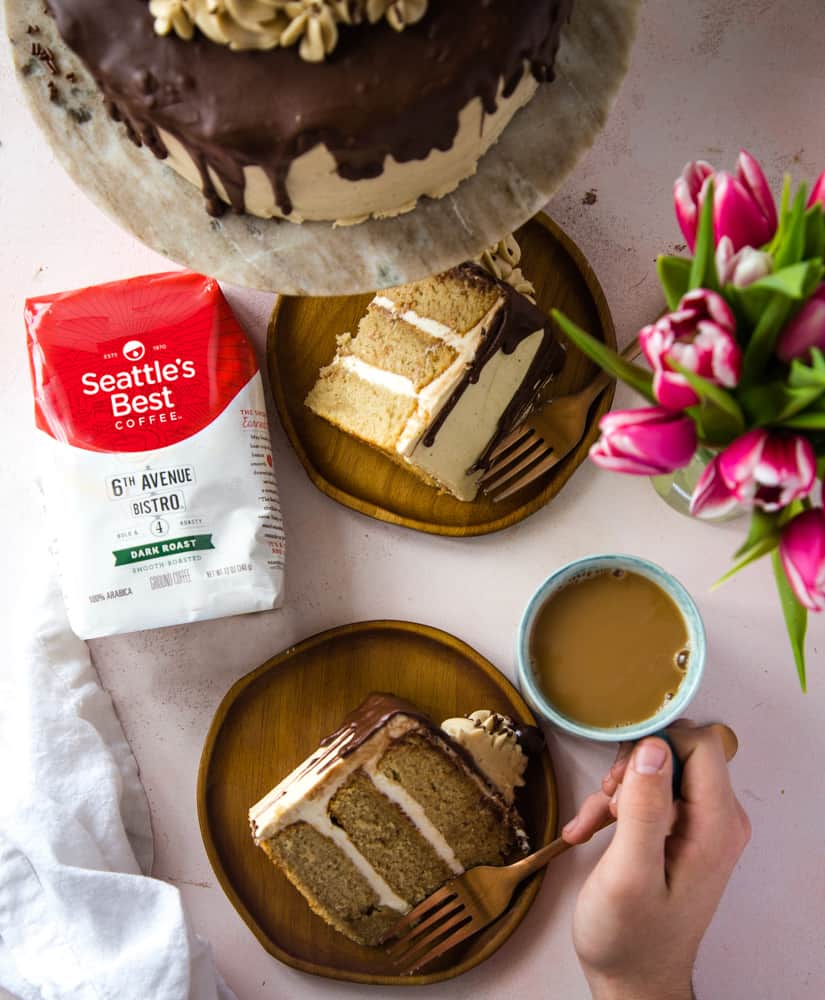 Overhead shot of the cake slices on wooden plates, a bag of Seattles best coffee, and a hand holding a cup of coffee.