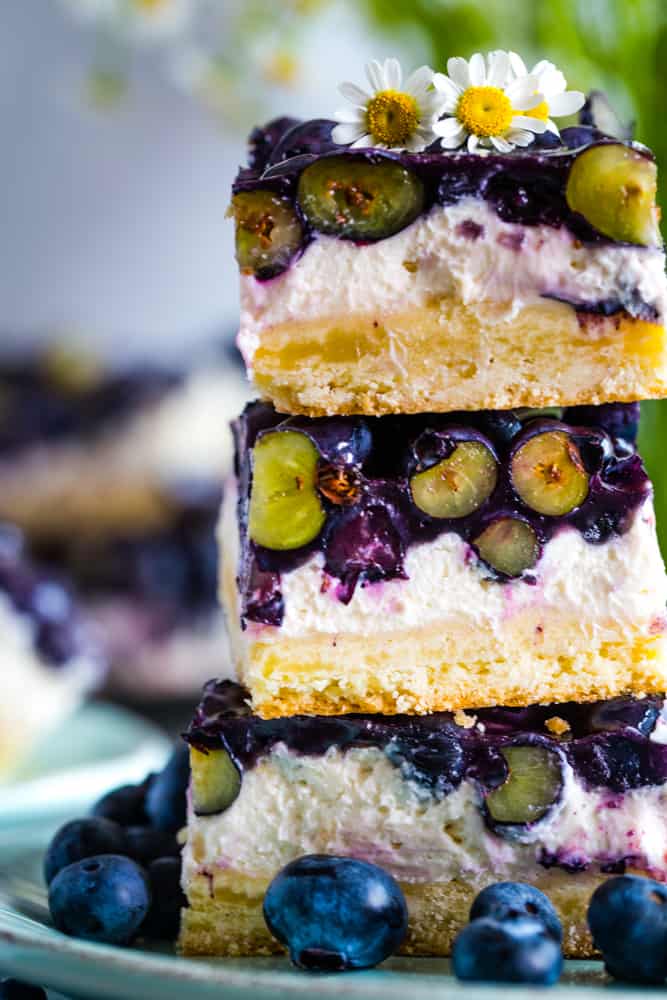 Three Blueberry Cream Cheese Bars stacked on top of each other showing the cut blueberries. 