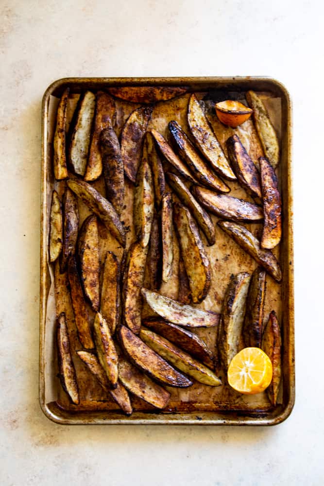 Overhead shot of the parchment lined pan with the browned potato wedges. 