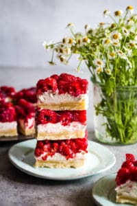 raspberry cream cheese bars stacked on a plate