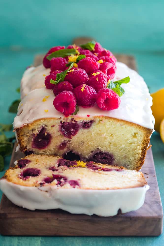 Pound cake with glaze and fresh strawberries on top partially cut to show inside. 