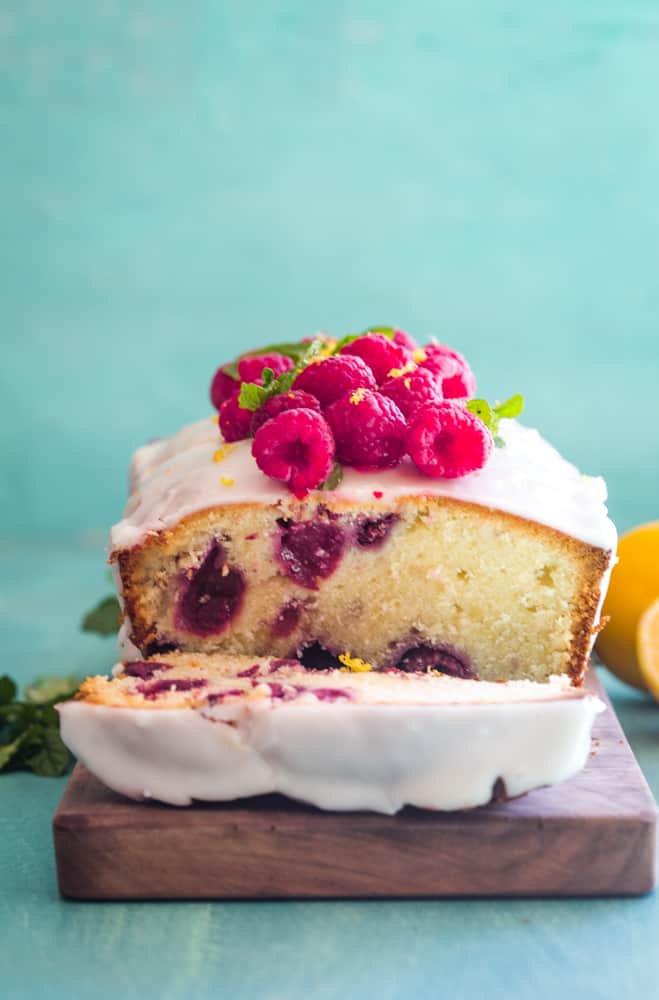 Raspberry Lemon Pound Cake on wood cutting board with one slice removed. 