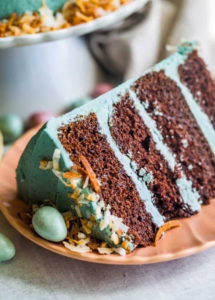 Up close shot of a sliced layer of cake on a peach plate with teal robins eggs on top. 