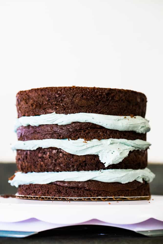 Unfrosted four cake layers stacked on a cake plate ready to frost. 