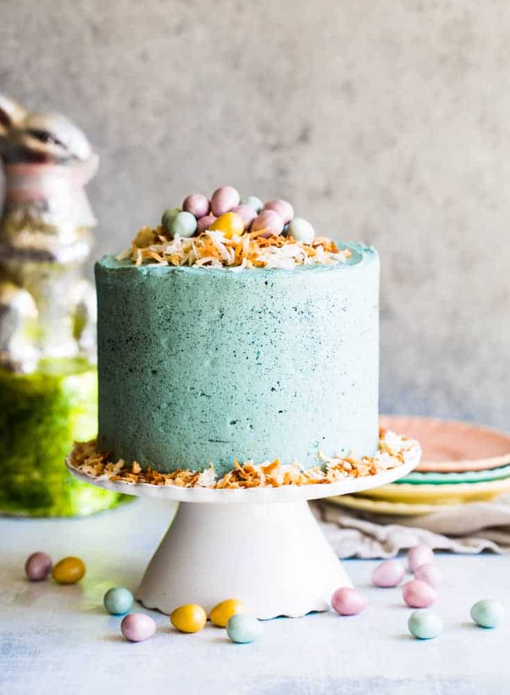 Chocolate Robin's Egg Easter cake topped with coconut and eggs on white cake stand. 