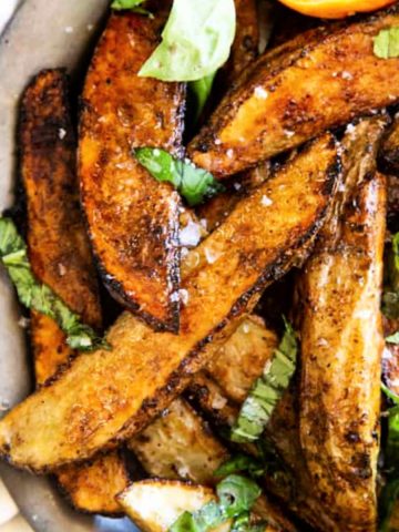 Square image of the browned crispy potato wedges on a metal plate.