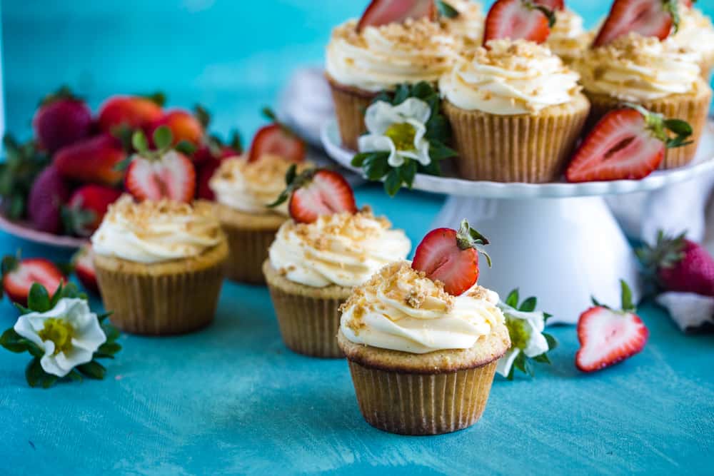 Cupcakes with frosting and fresh cut strawberry on a blue background. 