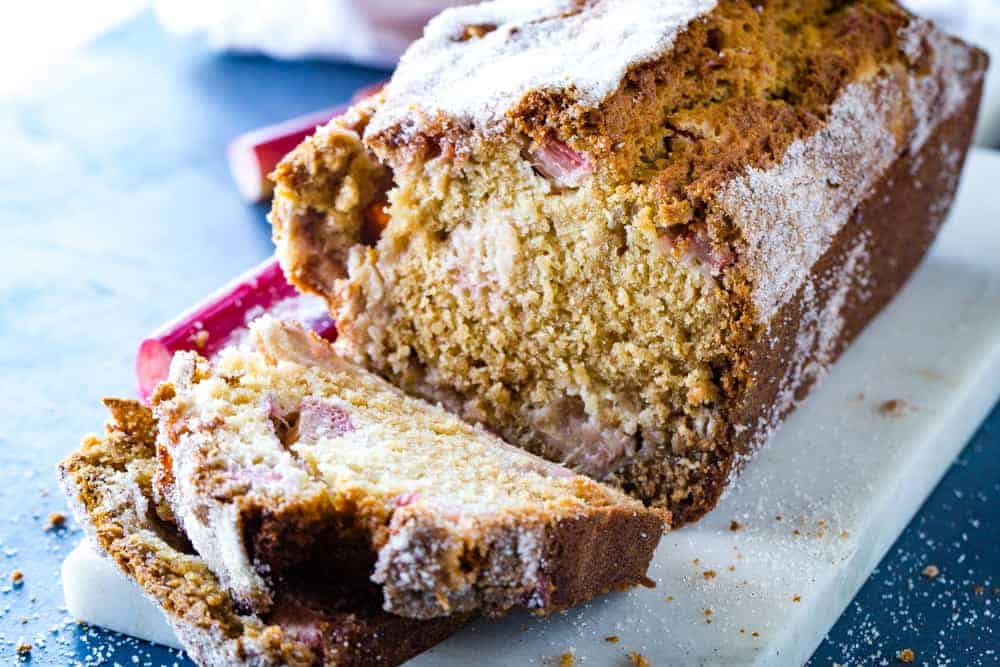 Rhubarb Streusel Bread cut into slices on a white marble board on blue background. 