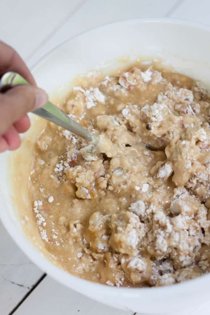 mixing the batter of the rhubarb streusel bread with a fork in large white bowl. 