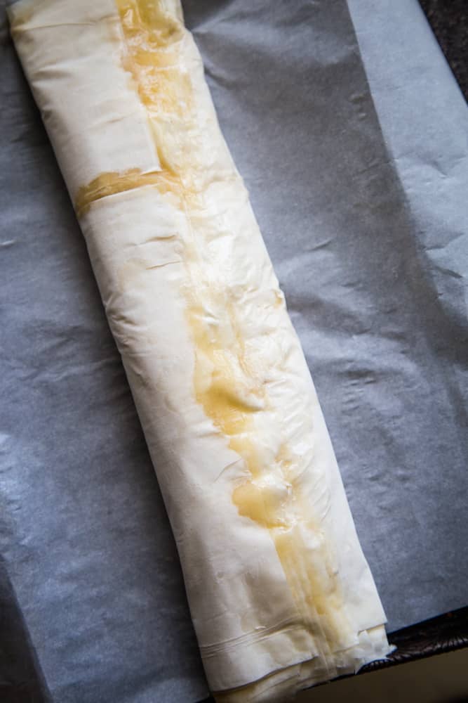 Rolling the apple strudel with phyllo dough before baking