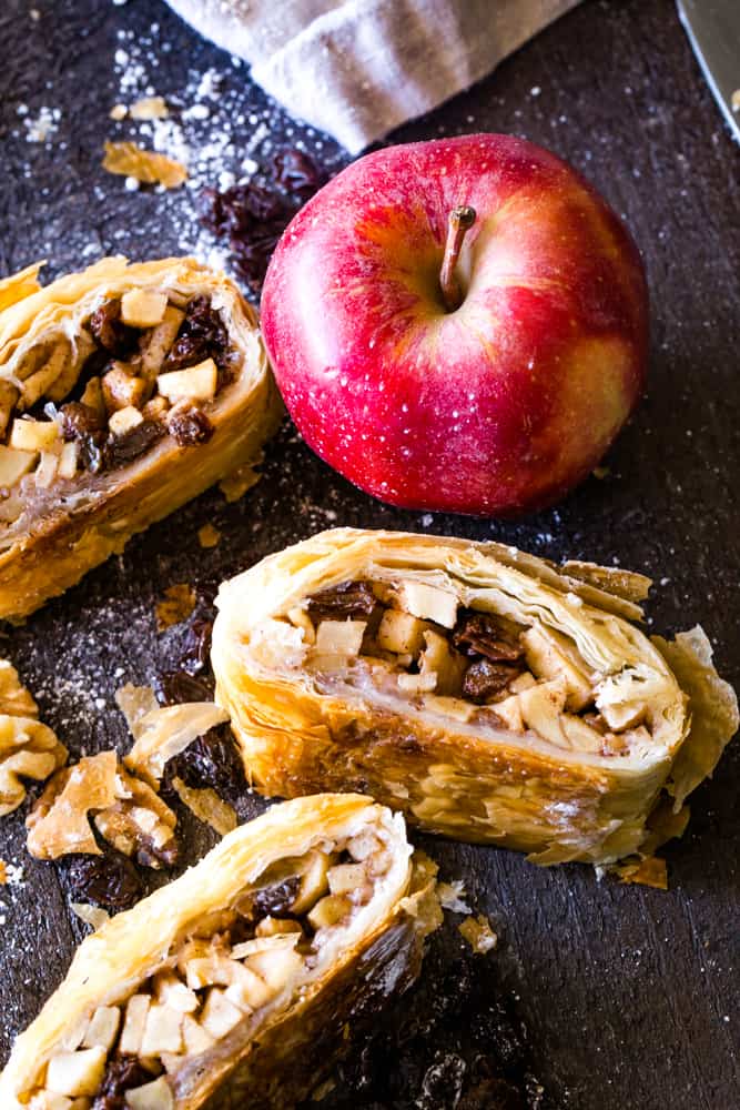 slices of apple strudel with phyllo dough next to a red apple